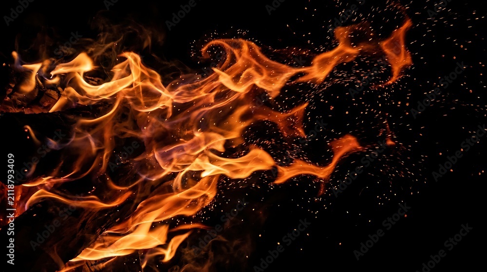 Fototapeta premium Bright orange flames and fire sparks burning with intense heat isolated against a deep solid black background