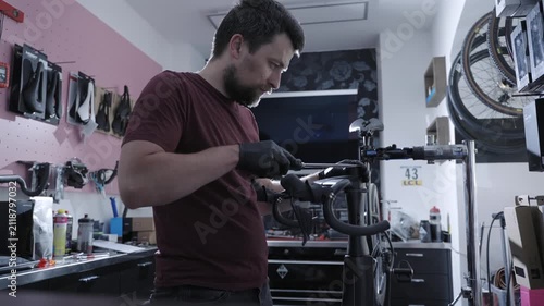 Master mechanic performing precision tuning on expensive black carbon road bike. Premium cycling gear service, mechanical tools workflow, expert maintenance and assembly in specialized workshop.