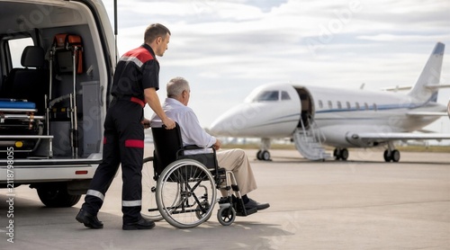 Paramedic Assisting Elderly Man in Wheelchair on Airport Tarmac