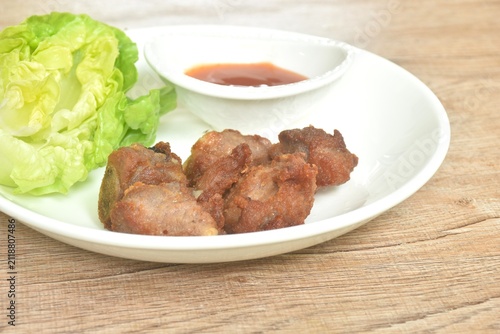 fried fermenting pork cartilage bone with garlic with cos lettuce salad dipping chili sauce on plate