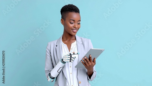 Confident businesswoman with cybernetic hand holding tablet on light blue background