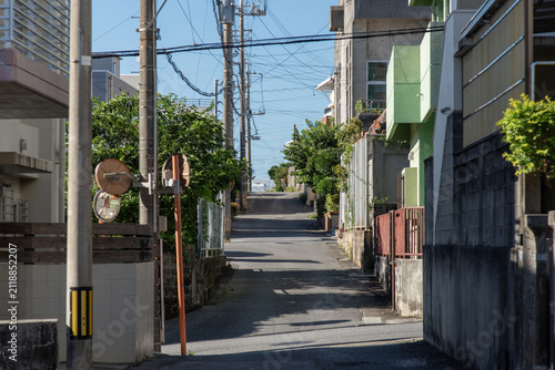 電柱や家々の影が道路にある天気の良い街の直線の路地裏の道