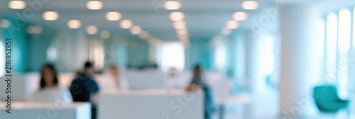 Blurry corporate workspace background with rows of desks and people for business presentation poster and website banner