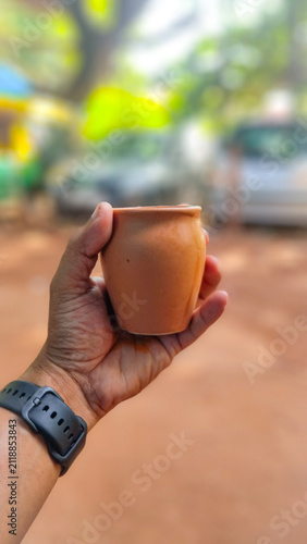 A hand holding a traditional clay cup (Kulhad) of hot masala chai on a peaceful roadside in Varkala, showcasing India's enduring tea culture and eco-friendly sustainable earthen cups