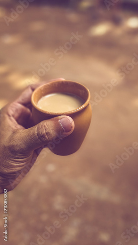 A hand holding a traditional clay cup (Kulhad) of hot masala chai on a peaceful roadside in Varkala, showcasing India's enduring tea culture and eco-friendly sustainable earthen cups
