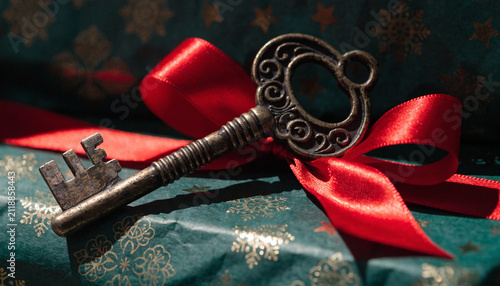 Elegant ornate key tied with festive red ribbon on decorative textured surface with showcases vintage style key adorned bold red satin bow resting richly patterned
