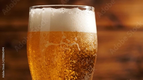 Close-up of a refreshing glass of golden beer with frothy head and bubbles