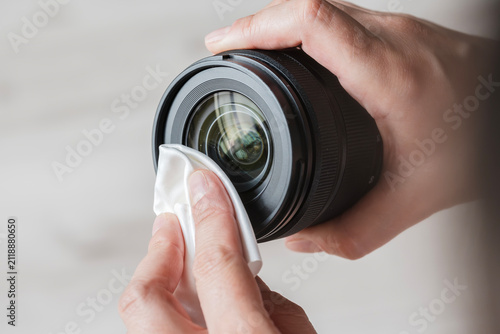 Person cleaning professional camera lens with cloth