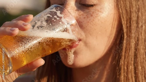 Woman with freckles drinking beer outdoors, close-up