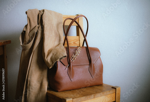 brown leather bag with a suede coat on a chair