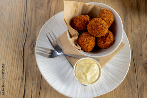 Bitterballen, Dutch meat-based snack in white plate served with mustard on wooden tabel background, Typically containing a mixture of beef or veal, Bitterballen are one of Holland's favorite snacks.