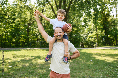 man and young boy playing american football on a court, teaching little player and spending time outdoors