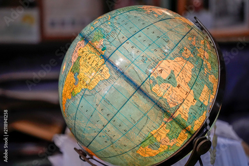 Illuminated vintage globe displaying detailed world map, continents and ocean currents on a desk; evokes travel, geography study, education, exploration and nostalgic home or office decoration.