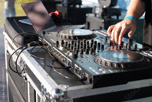 Foto Closeup shows DJ hands turning knobs and sliding faders on professional outdoor