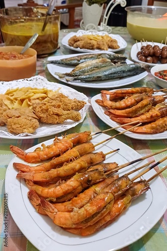 Bountiful feast of assorted seafood features grilled prawns on skewers, fried fish, and various snacks relates to culinary celebration for lifestyle magazines, travel blogs, restaurant marketing
