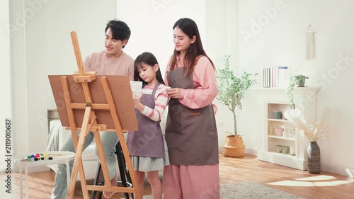 Girl Enjoys Painting With Parents at Home During a Family Activity