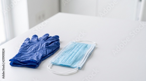 Blue medical gloves and face mask on white table.
