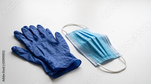 Blue nitrile gloves and surgical mask on white background.