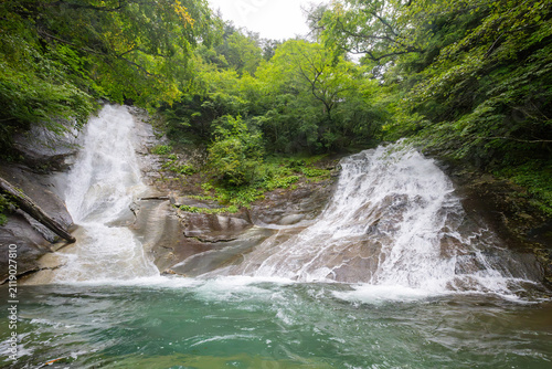 Twin Waterfalls Cascading Over Smooth Rock Ledges into a Turquoise Mountain Stream Surrounded by Lush Green Forest in Japan
