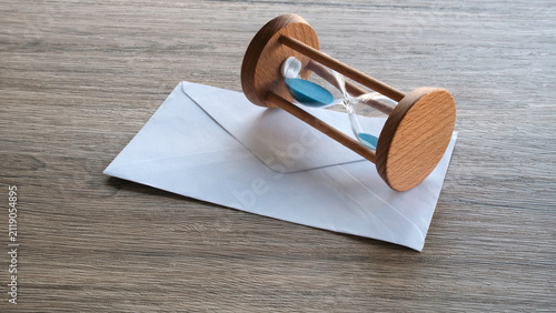 Wooden Sand Hourglass Resting on White Mail Envelope