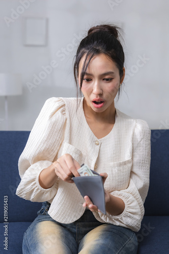 Картината върху платно Surprised young woman checking cash in her wallet at home, representing personal finance, budgeting, money management, financial shortage, household expenses, savings, economic uncertainty