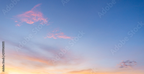 Vibrant Sunset Sky with Colorful Clouds and Gradient Blue Horizon,A breathtaking view of a vibrant sunset sky featuring a smooth gradient from deep blue to bright golden yellow, accented with soft,