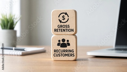 Wooden blocks illustrating gross retention and recurring customers concept on a workspace desk with laptop and plant