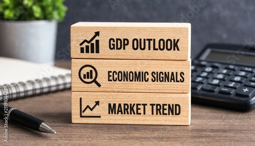Wooden blocks displaying economic indicators like GDP outlook market trend and economic signals on a workspace desk