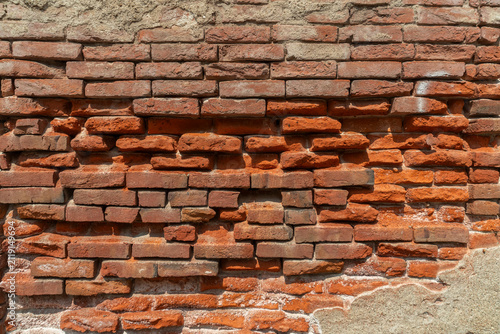 Foto ​Horizontal photo of an ancient damaged red brick wall with eroded mortar and pe