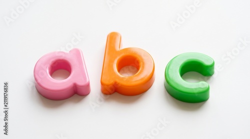 Bright pink, orange, and green plastic toy letters forming a, b, and c isolated on a clean white background, perfect for early childhood education and learning concepts.