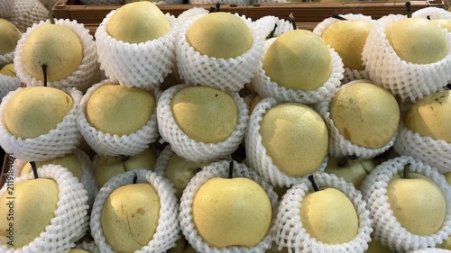 Fresh white pears, each wrapped in a protective foam net, are neatly arranged for display.