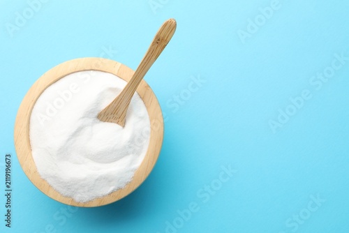 Bild auf Leinwand Baking soda and spoon in wooden bowl on light blue background, top view
