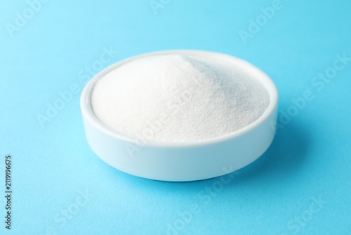 Foto Baking soda in bowl on light blue background, closeup