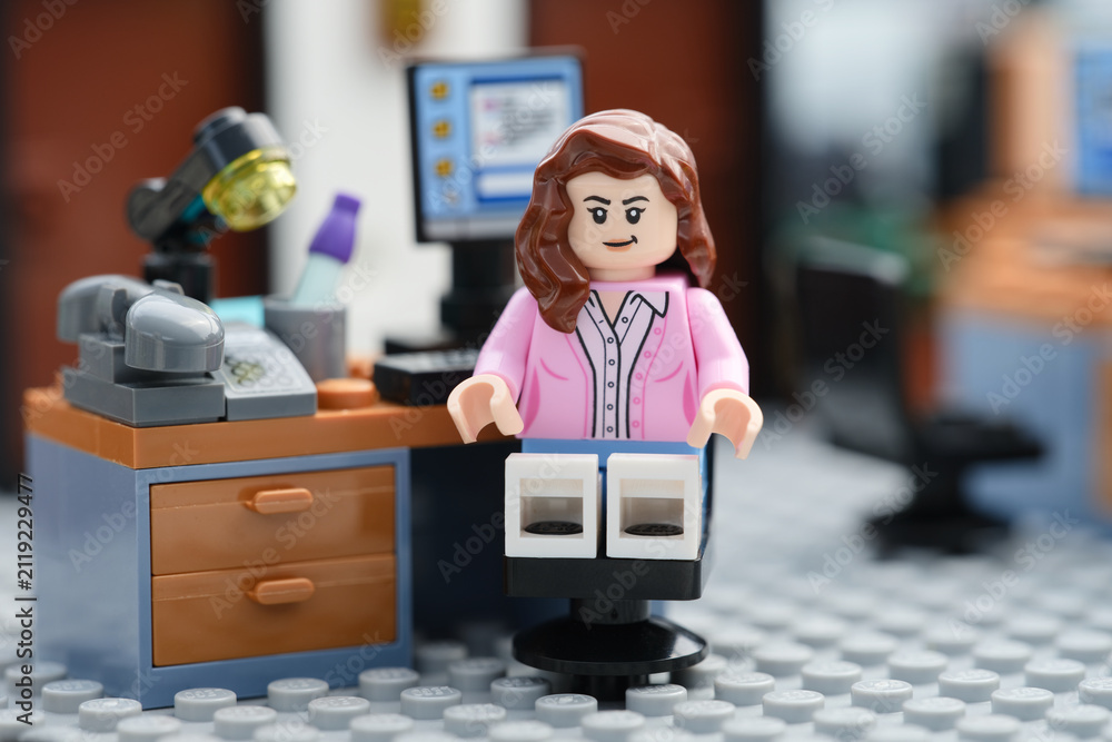 Fototapeta premium Tambov, Russian Federation - July 30, 2026 A happy Lego businesswoman minifigure sitting on a chair behind a computer in an office and looking at the camera. Close up.