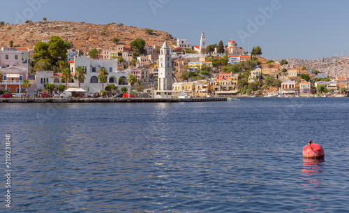 Foto View of the waterfront with the historic clock tower and colorful hillside houses in Symi Harbor, Dodecanese, Greece