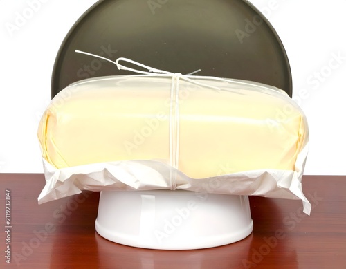 Large block of fresh yellow butter tied with string on a white pedestal stand