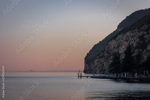 Peaceful Sunset over Lake Garda with Rocky Shoreline and Cliffs, Italy