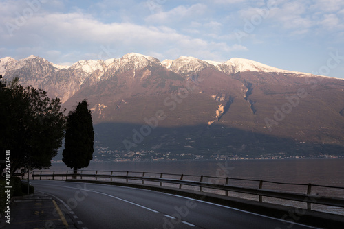 Scenic Road Along Lake Garda with Snow-Capped Mountains at Sunset, Italy