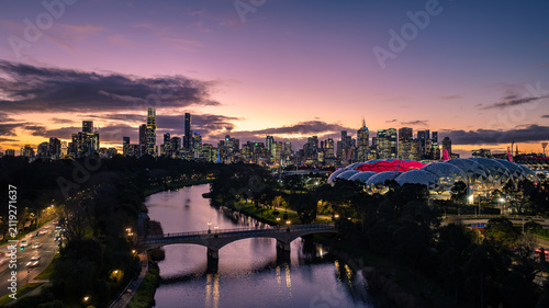 Aerial view of AAMI Park and the Melbourne skyline illuminated at sunset with the Yarra River and a bridge in the foreground in Melbourne, Victoria, Australia.