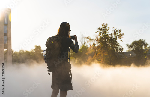 Traveler photographing cooling mist fountain with smartphone at sunset, Almaty Kazakhstan