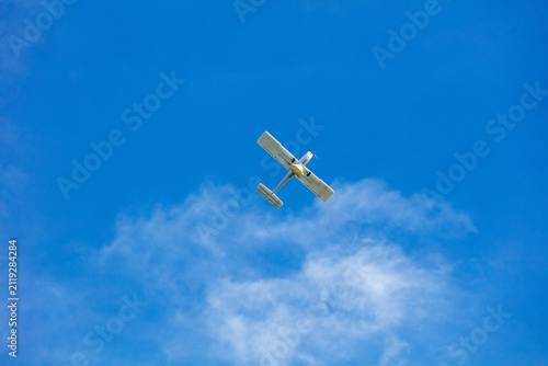View of a small light aircraft flying against a clear blue sky with scattered clouds over Vilnius, Vilnius County, Lithuania.