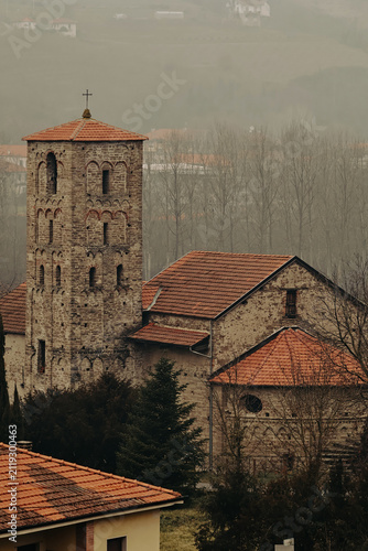 Stone church in Cortemilia, in the Province of Cuneo. Spring view with overcast skies and light haze highlighting historic Italian architecture, stone masonry and the quiet atmosphere of the countrysi