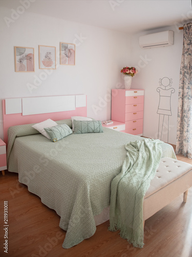 Pretty boho styled bedroom with fresh cut flowers and pink sheepskin