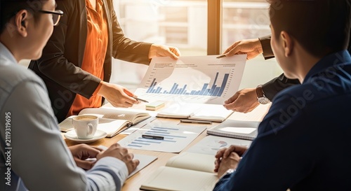 Diverse business team collaborating on a project strategy while reviewing financial charts and documents in a modern office