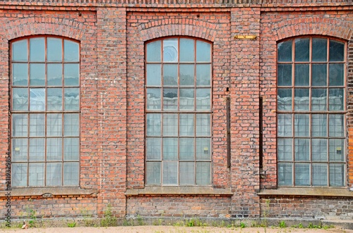 Cuadro en lienzo Historic brick industrial facade with tall arched factory windows, weathered mas