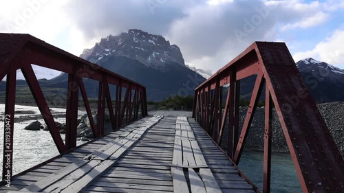 A slow-motion clip showing the crossing of a bridge over a river with clear blue water in Argentine Patagonia; the footage was shot from a car that does not appear in the frame.