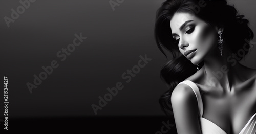 Brunette in a white dress on a dark background, black and white photo.