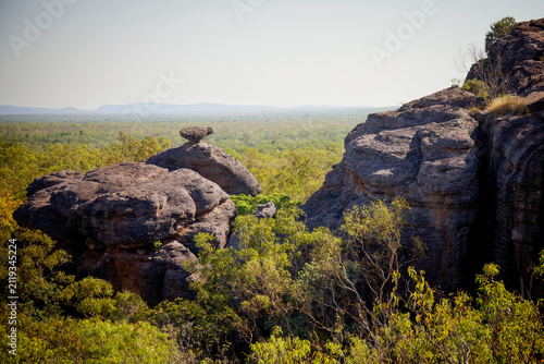 Foto Weathered sandstone rock formations rise above a dense, lush green bushland canopy