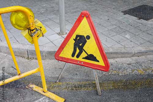 Fotografie Roadwork warning sign stands roadside