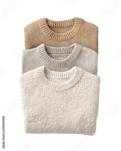 Stack of three folded knitted crewneck sweaters in beige gray and cream isolated on transparent background